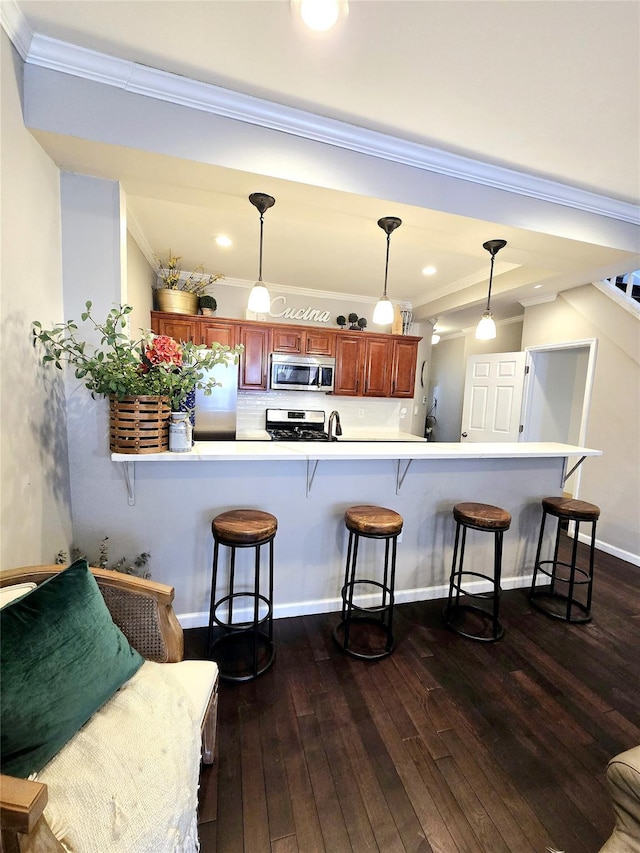 kitchen with decorative light fixtures, a breakfast bar area, dark hardwood / wood-style flooring, kitchen peninsula, and stainless steel appliances