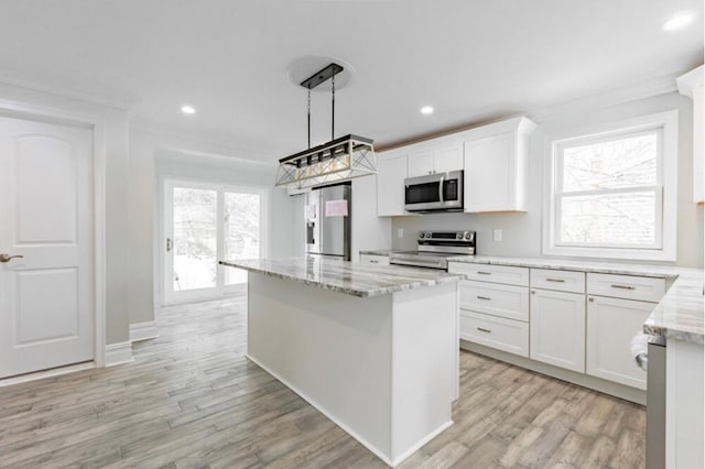 kitchen with stainless steel appliances, light stone counters, white cabinets, decorative light fixtures, and light wood-type flooring