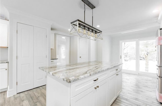 kitchen featuring white cabinetry, refrigerator, a center island, light hardwood / wood-style flooring, and light stone countertops