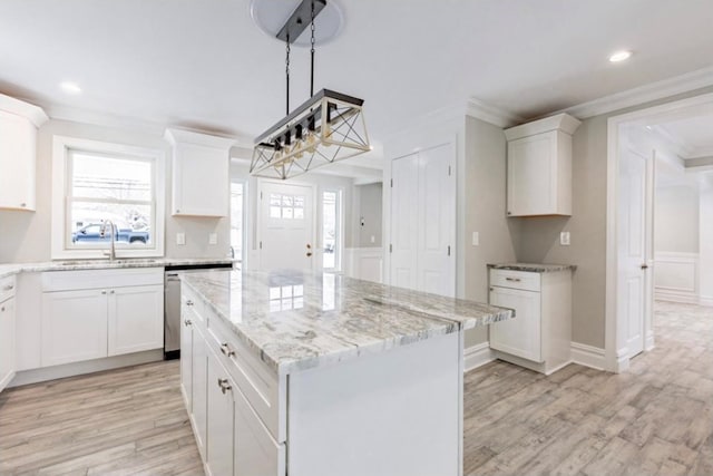 kitchen with sink, ornamental molding, dishwasher, a kitchen island, and white cabinets