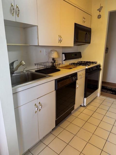 kitchen featuring white cabinetry, sink, black appliances, and light tile patterned flooring