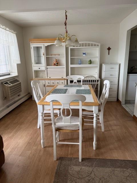 dining area featuring wood-type flooring, a baseboard heating unit, sink, and an inviting chandelier