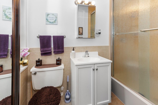 full bathroom with tile walls, vanity, enclosed tub / shower combo, and toilet