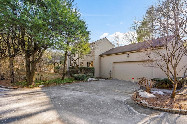 view of side of home with driveway, an attached garage, and stucco siding