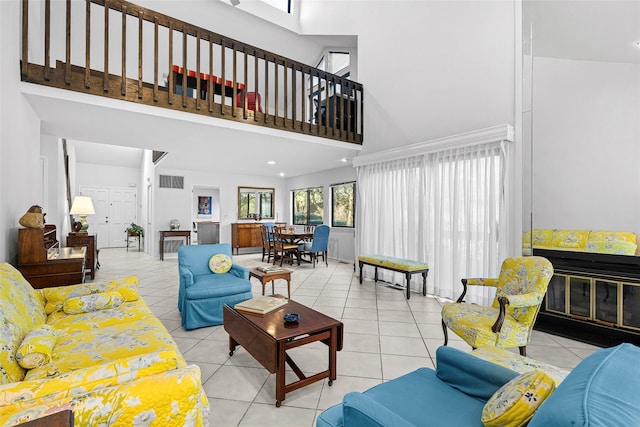 living room featuring light tile patterned floors, visible vents, and a towering ceiling