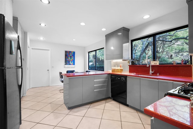 kitchen featuring light tile patterned floors, gray cabinetry, a peninsula, a sink, and black appliances