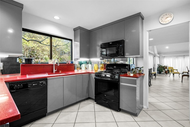 kitchen featuring light tile patterned floors, recessed lighting, gray cabinetry, a sink, and black appliances