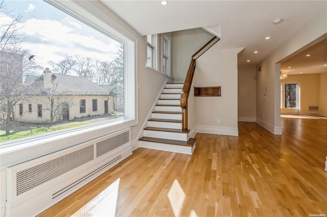 staircase with hardwood / wood-style flooring and radiator heating unit