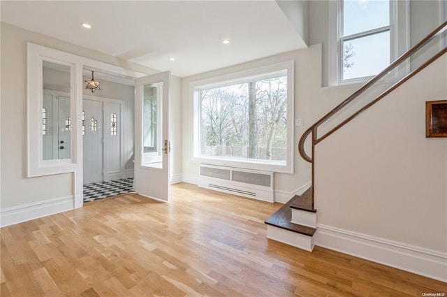 entrance foyer featuring a chandelier, a wall unit AC, and light hardwood / wood-style flooring