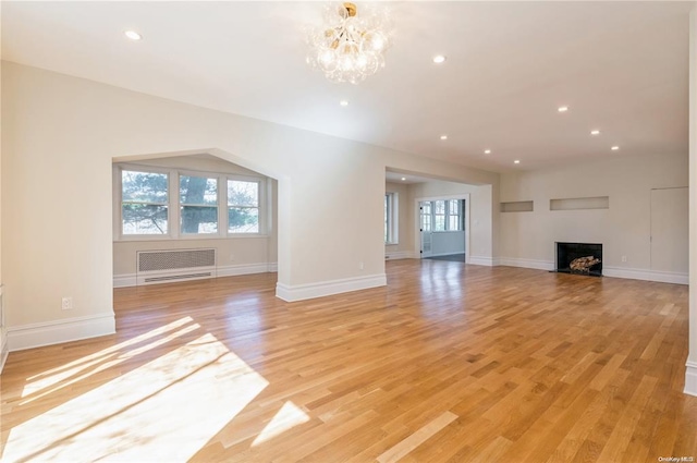 unfurnished living room with a chandelier and light wood-type flooring