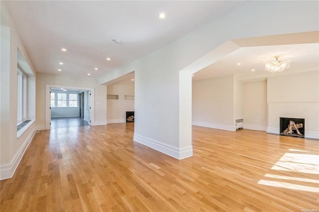 unfurnished living room featuring a chandelier and light hardwood / wood-style flooring