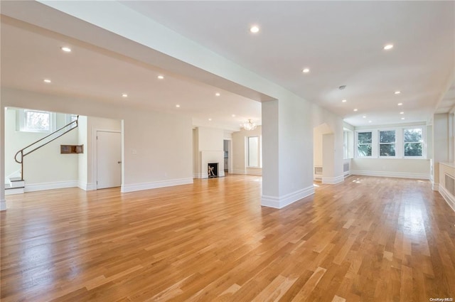 unfurnished living room featuring an inviting chandelier and light hardwood / wood-style flooring