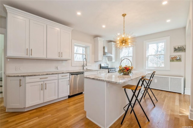 kitchen with stainless steel appliances, decorative light fixtures, a kitchen island, and white cabinets