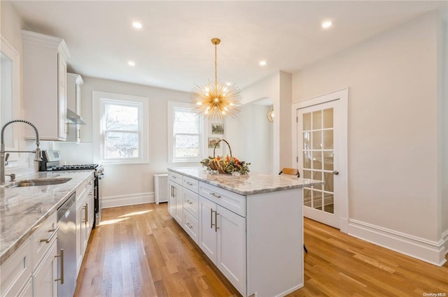 kitchen featuring pendant lighting, sink, white cabinets, and a kitchen island