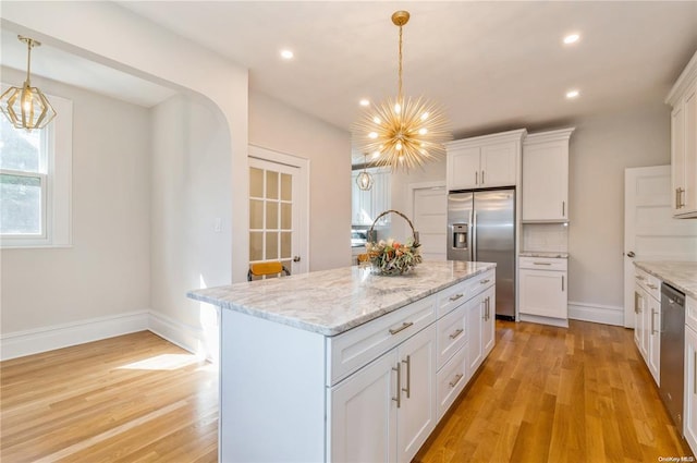 kitchen with white cabinetry, stainless steel appliances, a center island with sink, decorative light fixtures, and a chandelier