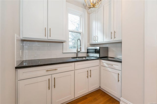 kitchen with white cabinetry, sink, decorative backsplash, and light hardwood / wood-style floors