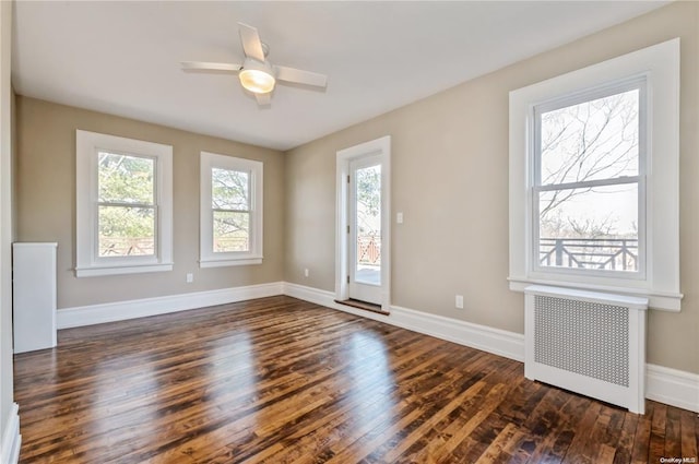 unfurnished room with dark hardwood / wood-style flooring, radiator heating unit, and ceiling fan