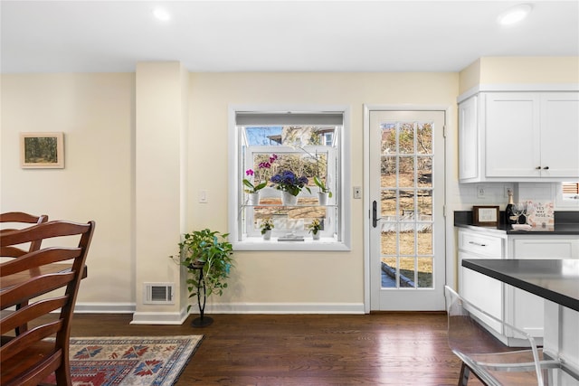 dining room featuring dark wood finished floors, visible vents, and baseboards