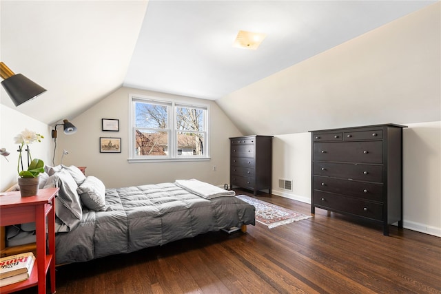 bedroom with visible vents, lofted ceiling, baseboards, and dark wood-style floors