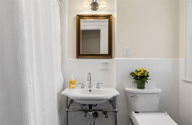 full bathroom with a sink, a wainscoted wall, toilet, and tile walls