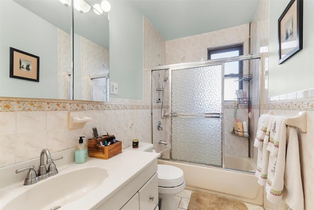 full bathroom with toilet, shower / bath combination with glass door, tile walls, vanity, and tile patterned flooring