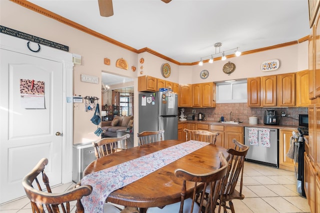 kitchen featuring sink, crown molding, tasteful backsplash, light tile patterned floors, and stainless steel appliances