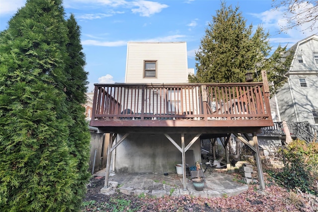 back of property with a wooden deck and a patio area