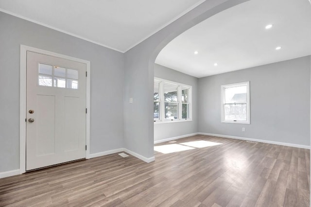 foyer entrance with ornamental molding and light hardwood / wood-style floors