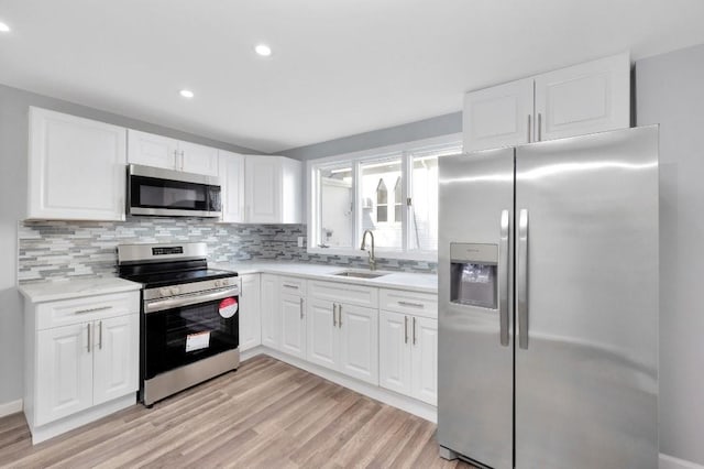 kitchen with stainless steel appliances, white cabinetry, sink, and backsplash