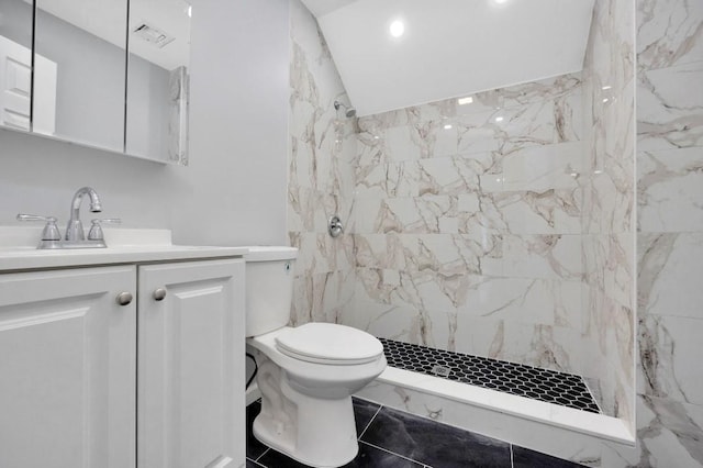 bathroom with vanity, tiled shower, and toilet