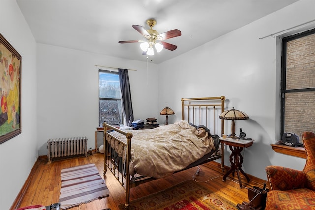 bedroom with wood-type flooring, radiator heating unit, and ceiling fan