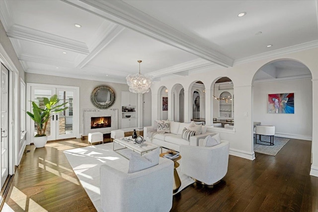 living area with ornamental molding, beamed ceiling, a lit fireplace, and wood finished floors