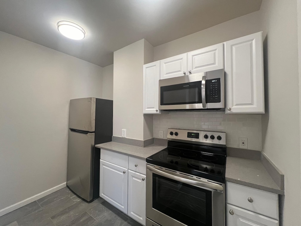 kitchen with tasteful backsplash, white cabinetry, and appliances with stainless steel finishes