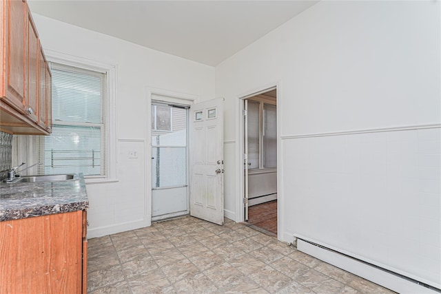 interior space with tile walls, a baseboard heating unit, and sink