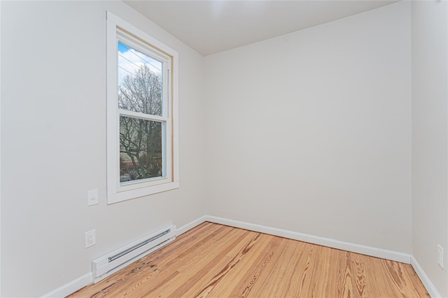 empty room featuring a baseboard radiator and light hardwood / wood-style floors