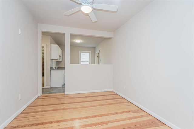 empty room with ceiling fan and light hardwood / wood-style flooring