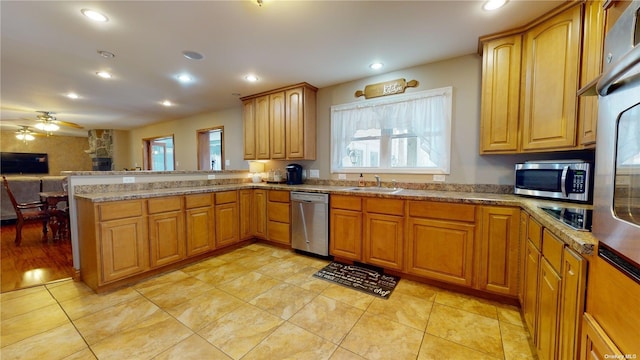 kitchen featuring sink, light stone counters, kitchen peninsula, ceiling fan, and stainless steel appliances