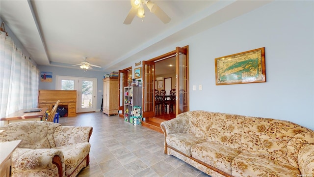 living room featuring a raised ceiling and ceiling fan