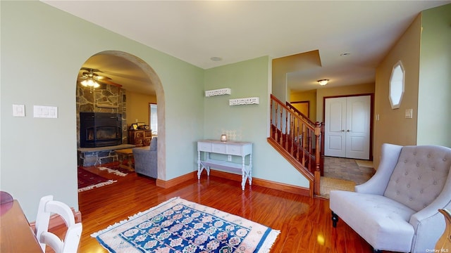 living area with wood-type flooring, ceiling fan, and a fireplace