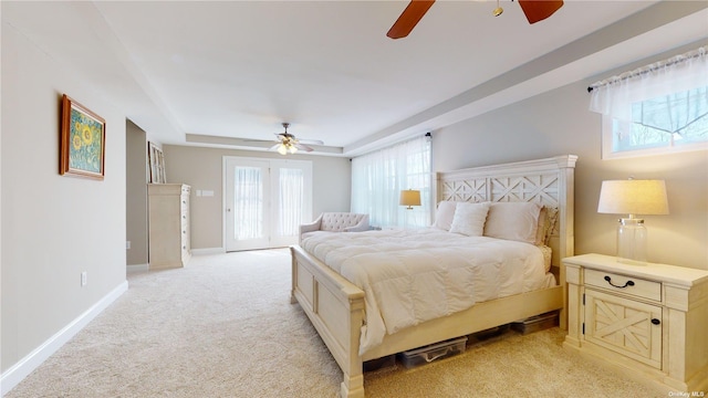 carpeted bedroom with ceiling fan, a raised ceiling, multiple windows, and access to outside