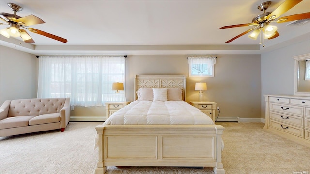 bedroom with light carpet, a baseboard heating unit, a raised ceiling, and ceiling fan