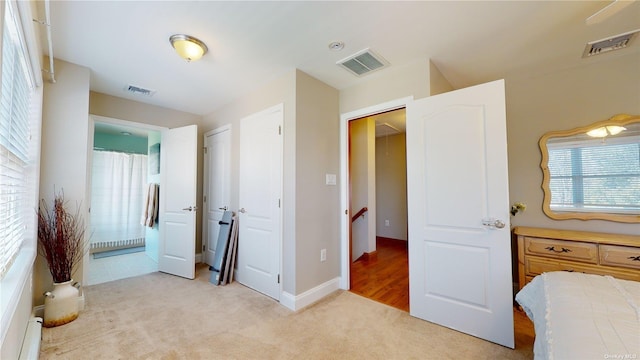 bedroom featuring connected bathroom, light colored carpet, and baseboard heating