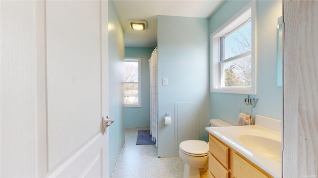 bathroom with vanity, a wealth of natural light, tile patterned floors, and toilet