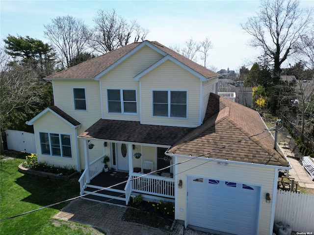 view of front of home with a garage, covered porch, a shingled roof, and fence