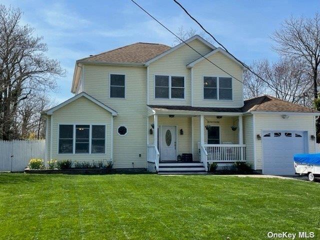 view of front facade featuring a porch, a front lawn, an attached garage, and fence