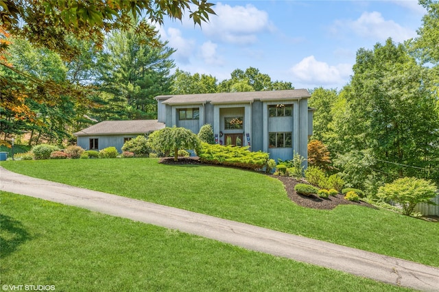 view of front of house with a front yard, concrete driveway, and stucco siding