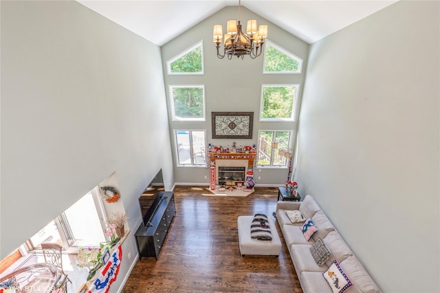 living area featuring a chandelier, high vaulted ceiling, a fireplace with flush hearth, wood finished floors, and baseboards