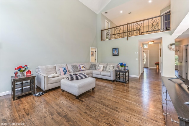 living area with high vaulted ceiling, baseboards, and wood finished floors