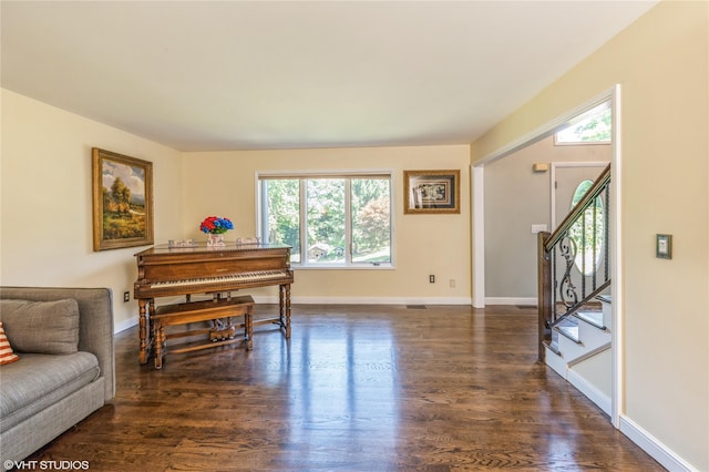 sitting room with stairs, baseboards, and dark wood-style flooring