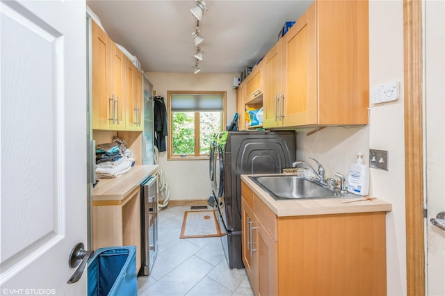 laundry room with light tile patterned floors, a sink, washer and dryer, cabinet space, and rail lighting